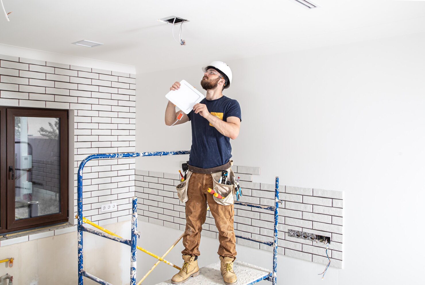 constructor electricista barba trabajador casco blanco trabajo instalacion lamparas altura profesional monos taladro sitio reparacion 169016 8628